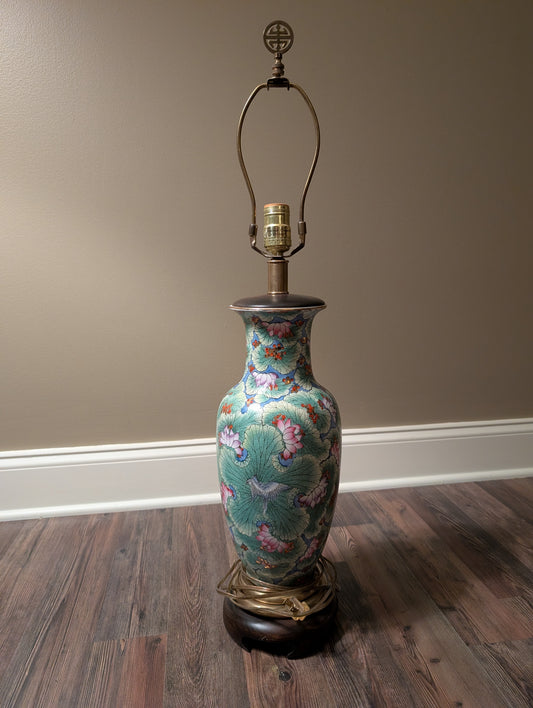 Decorative vase lamp with floral patterns on a wooden floor against a beige wall.