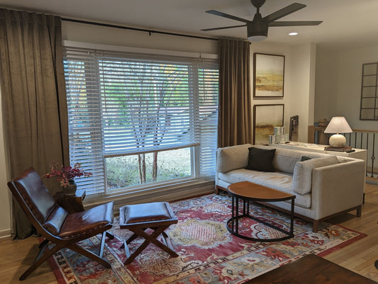 Living room with a couch, coffee table, and large window with blinds.