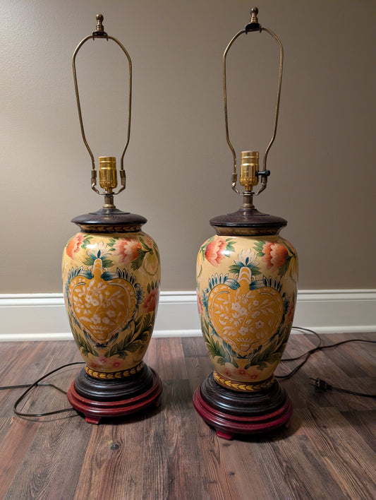 Pair of hand painted decorative vintage lamps with floral designs on a wooden floor.